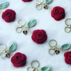 crocheted keychains with red roses and green leaves attached to them on a white surface