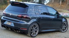 the rear end of a black volkswagen golf gtr parked in front of some rocks