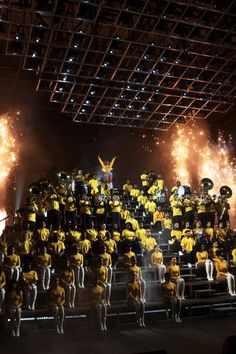 a large group of people standing on top of a stage with fireworks in the background