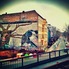 a large mural on the side of a building next to a street with cars driving down it