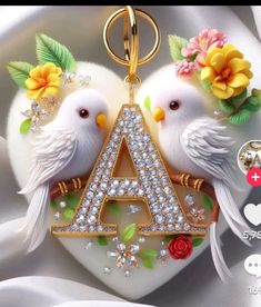 two white birds sitting on top of a heart shaped keychain with flowers and leaves