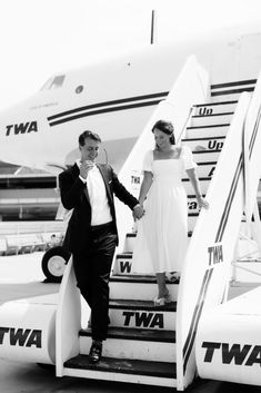 a man and woman standing on the steps of an airplane