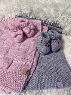 two knitted baby blankets with pink and grey ones on them, one is laying next to the other