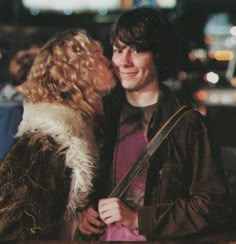 a man and woman standing next to each other in front of a street at night