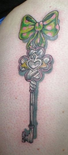 a tattoo on the back of a woman's shoulder with a key attached to it