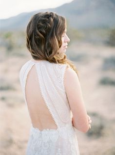 the back of a woman's dress in an open desert area with mountains in the background