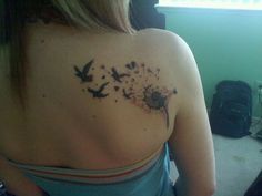 the back of a woman's shoulder with birds flying around it and on top of her