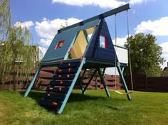 there is a blue and yellow play structure in the grass with stairs leading up to it