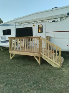 a wooden deck next to an rv parked in the grass