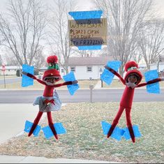 two red and blue paper dolls in front of a sign