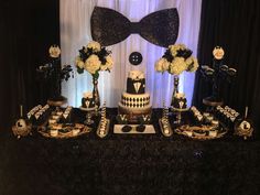 a black and white dessert table with flowers, cake, and bow tie decorations on it