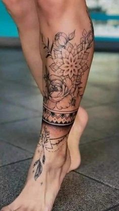 a woman's legs with tattoos and flowers on her leg, in front of a tiled floor