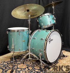 a blue drum set sitting on top of a rug next to a black wall and floor