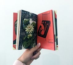 a person is holding an open book in their hand and it has flowers on the cover