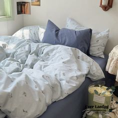 an unmade bed with blue sheets and pillows