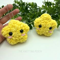 two small yellow crocheted animals with black eyes are being held by a hand