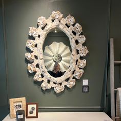 there is a mirror on the wall above a table with pictures and other items in front of it