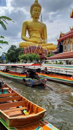 boats are lined up in front of a large buddha statue