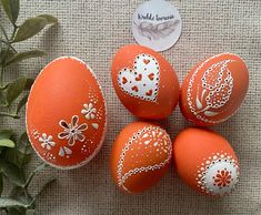 four orange painted eggs with white designs on them