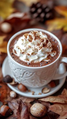 there is a cup of hot chocolate with whipped cream on top and nuts around it