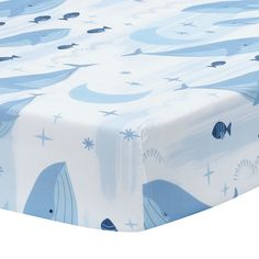 a blue and white crib bed sheet with fish on the water, stars and circles