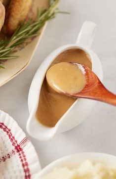 a spoon full of gravy sitting on top of a plate next to some bread