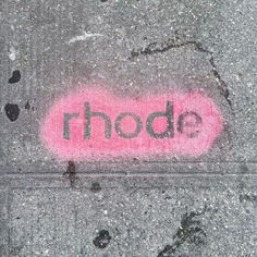 the word rhode is painted on the sidewalk with pink paint and paw prints