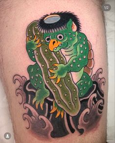 a man's leg with a green and yellow tattoo design on it, which has an image of a creature holding a fish