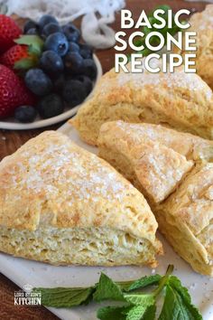 some scones are sitting on a white plate with berries and mint leaves next to it