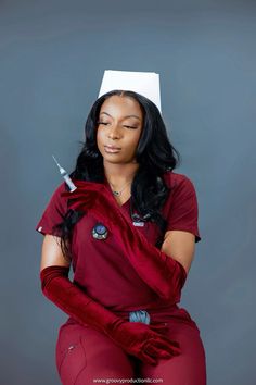 a woman in red scrubs with a white hat on her head and holding a sy