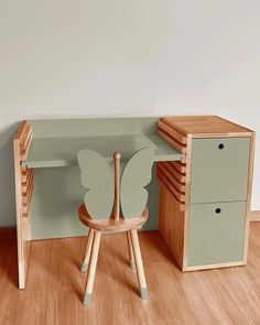 a wooden chair sitting next to a desk with a paper butterfly on top of it