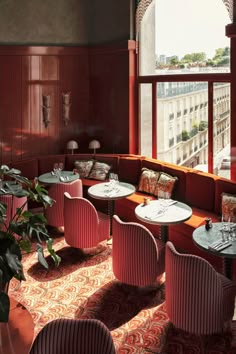 a restaurant with red walls and chairs, potted plants on the tables in front of them