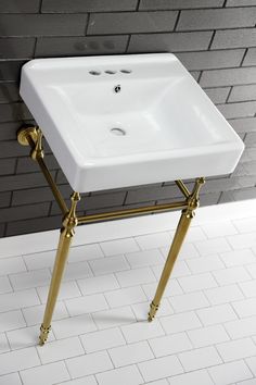 a white sink sitting on top of a metal stand in front of a brick wall