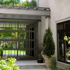 an outdoor dining area with potted plants on either side and sliding glass doors to the outside