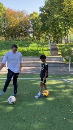 a man teaching a boy how to kick a soccer ball