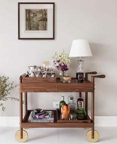 a bar cart with drinks and liquors on it in front of a framed photograph