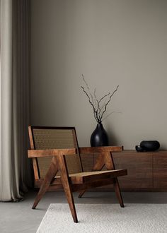 a wooden chair sitting next to a vase on top of a table