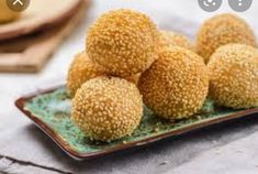 sesame seed balls on a plate next to a wooden spoon