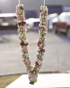 two flowers are hanging from a string in front of a parking lot with cars parked on the street