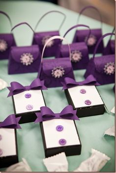 purple and white paper bags with buttons on them are sitting on a blue tablecloth