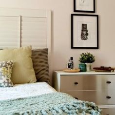 a bedroom with two pictures on the wall above the bed and dresser in front of it