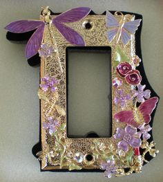 a decorative photo frame with flowers and dragonflys on the front, sitting on a table