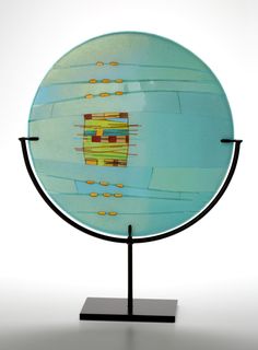 a glass plate on a metal stand with an abstract design in the center and yellow circles around it