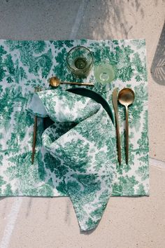 a place mat with spoons, utensils and a green napkin on it