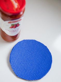 a blue round object next to a jar of peanut butter on a white table top