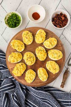 an overhead view of deviled eggs on a wooden platter with other ingredients around it