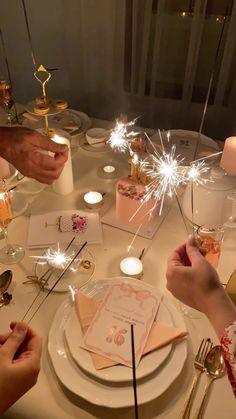 people sitting at a table with sparklers in the air over their plates and napkins