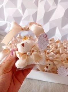 a hand holding a small teddy bear in a clear box with bows and tags on it