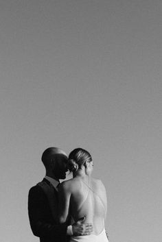 a man and woman standing next to each other in front of a clear blue sky