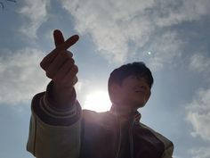 a man holding up his peace sign in front of the sun